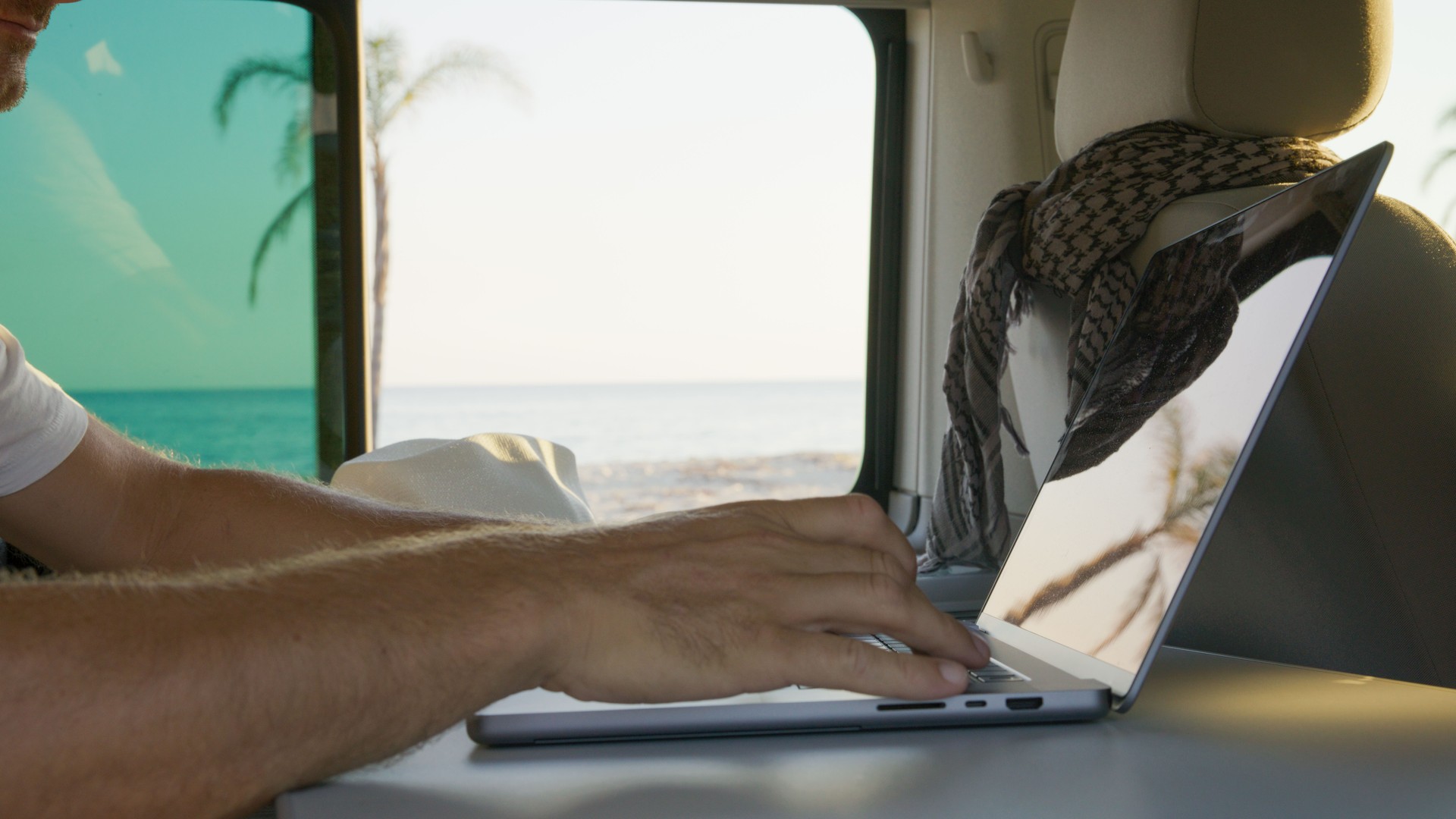 Man using laptop in motor home against beautiful sea